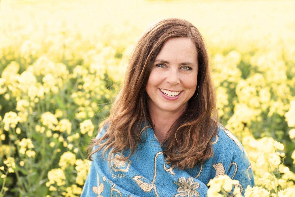 Mulher de 40 anos sorrindo em campo de flores amarelas | Como viver bem com a menopausa