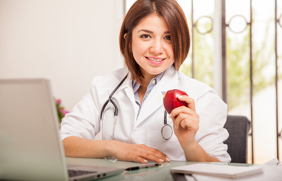 Médica sorridente com fruta na mão | 31 de março - Dia da Saúde e Nutrição